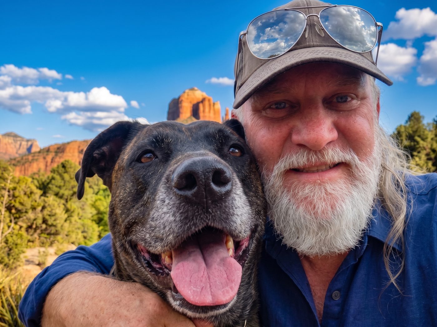 Charles Eakins outdoors with his dog Luna, red rock formations behind them.